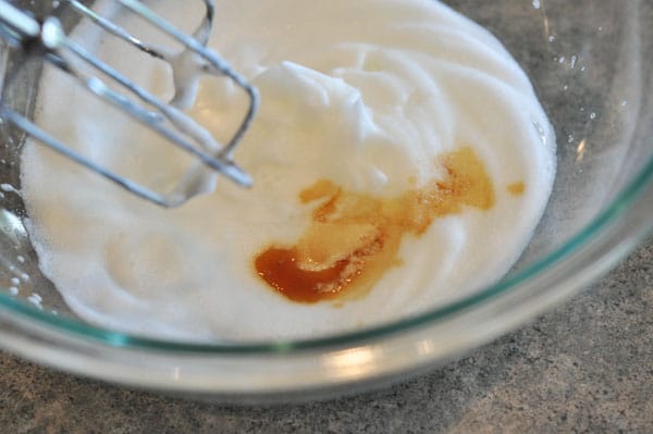 beaten egg whites and vanilla extract in a glass bowl