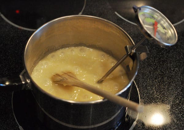 melted butter in a saucepan with a wooden spoon and candy thermometer clipped to the side of the pan