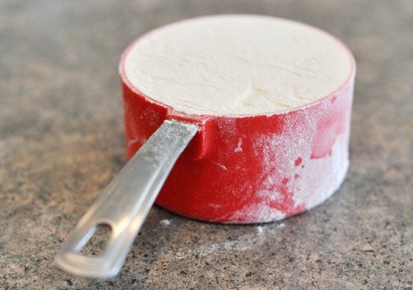 a red measuring cup full of white flour