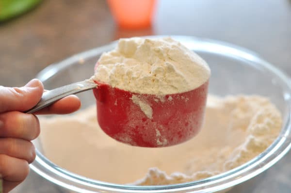 a red measuring cup overfilled with white flour