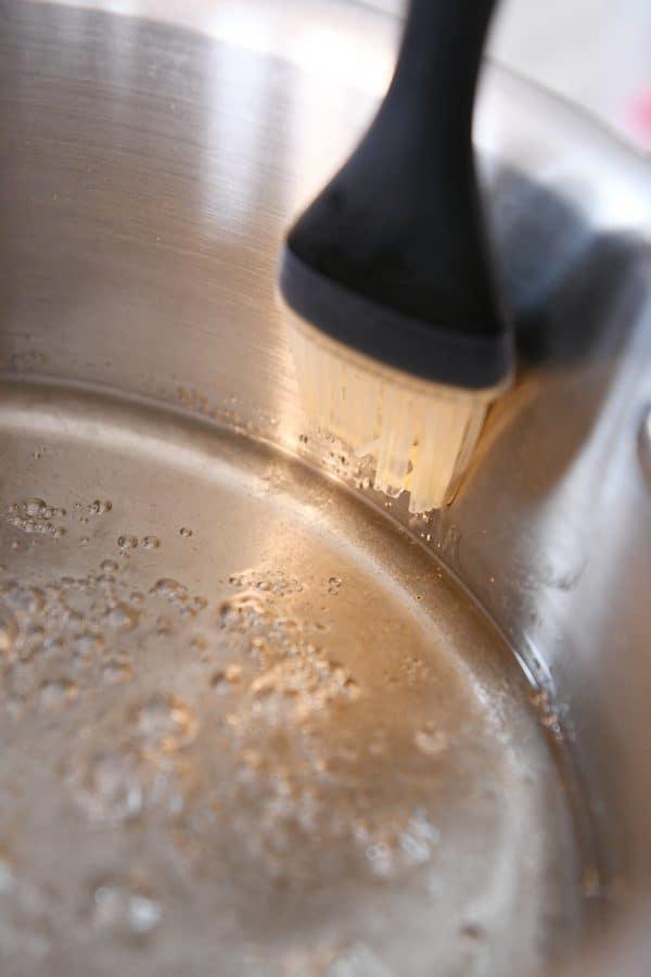 Brushing sugar crystals off sides of pan.