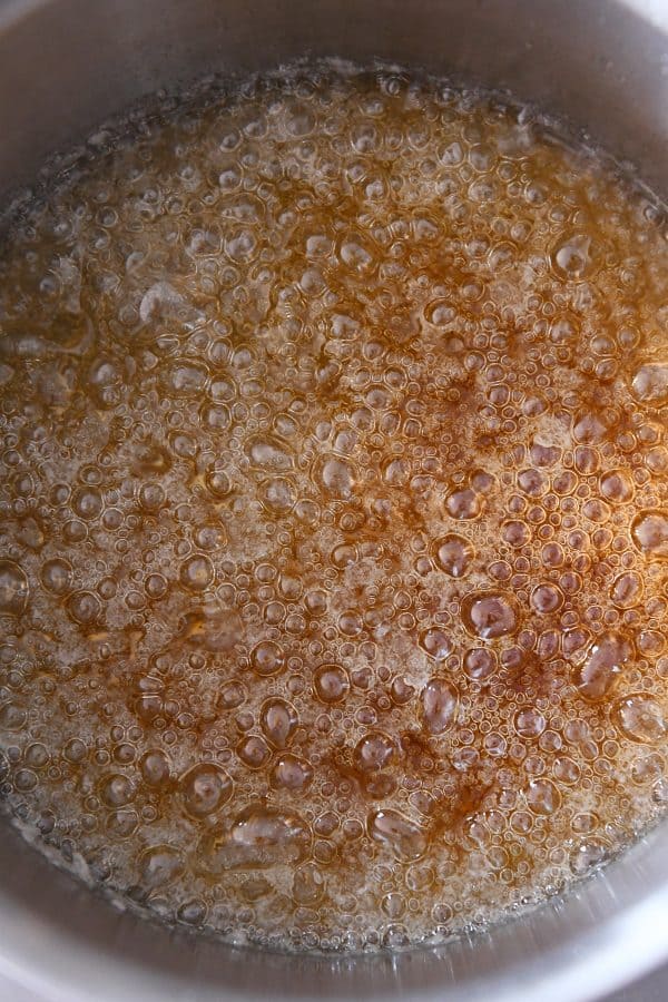 Cooking sugar mixture to amber brown for homemade caramel sauce.