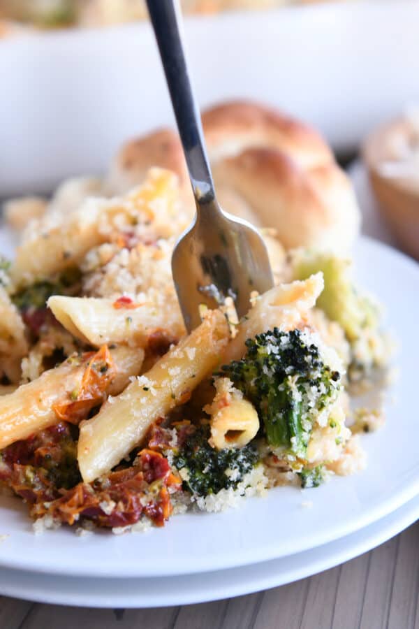 Fork taking bite of baked penne with chicken, broccoli, and smoked mozzarella.
