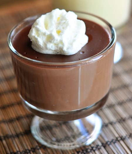 A glass dish with chocolate pudding topped with whipped cream.