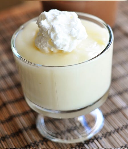 A clear dish with vanilla pudding and whipped cream on top.