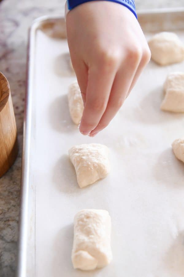 sprinkling easy homemade soft pretzel bites with salt before baking