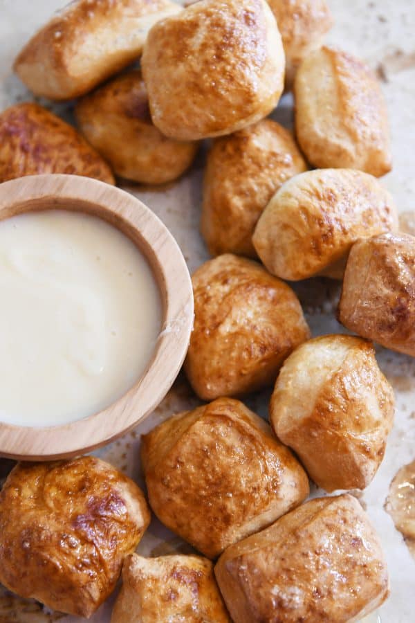 Easy homemade soft pretzel bites on sheet pan with bowl of cheese sauce.