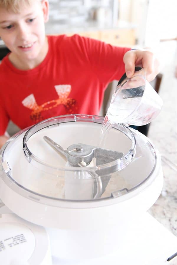 Pouring water into bosch mixer for easy homemade soft pretzel bites.