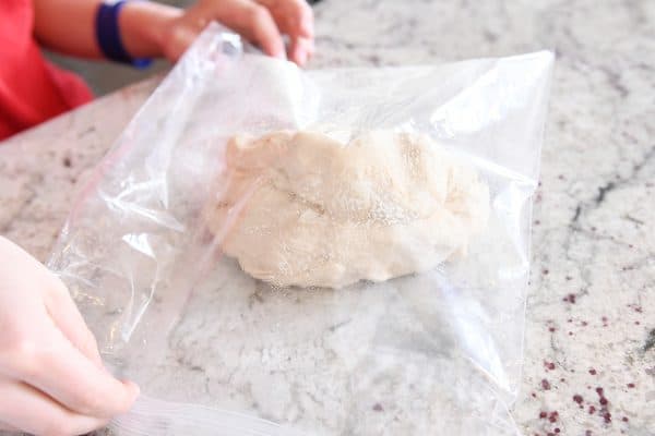 Putting pretzel bite dough in greased bag to rise.