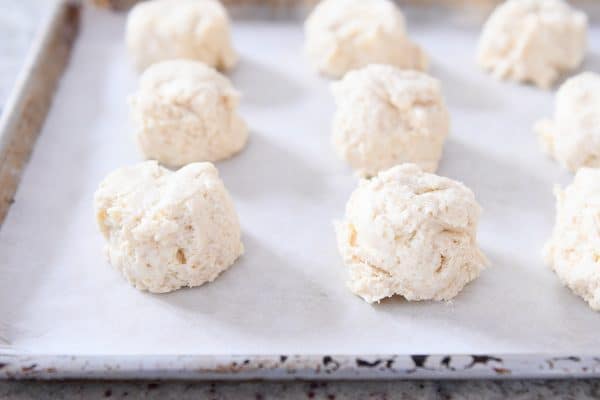 Mounds of buttermilk drop biscuits on parchment lined baking sheet