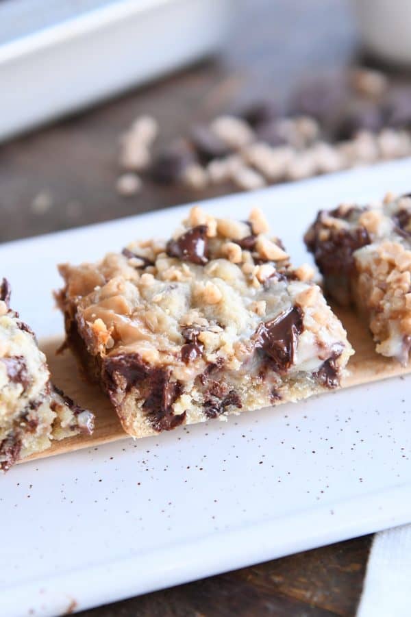 Three chocolate chip toffee bars on wood tray.