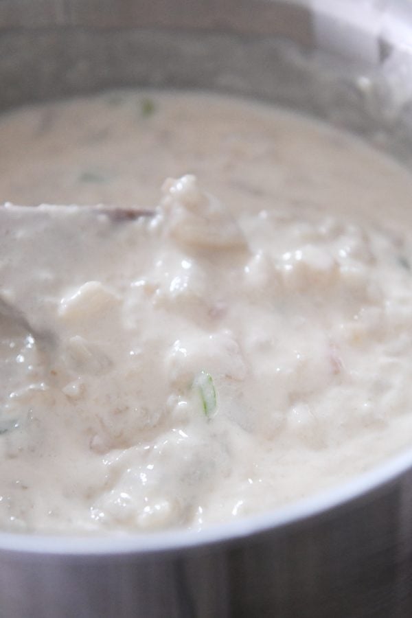 Stirring loaded baked potato soup in pot.