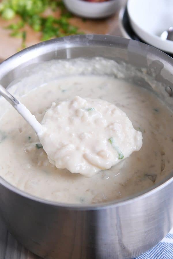 Scooping out ladle of easy loaded baked potato soup in pot.