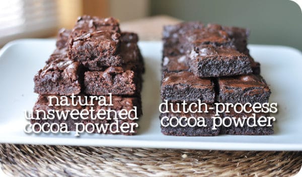 two stacks of cut brownies next to each other on a white platter labeled natural unstweetened cocoa power and dutch-process cocoa powder