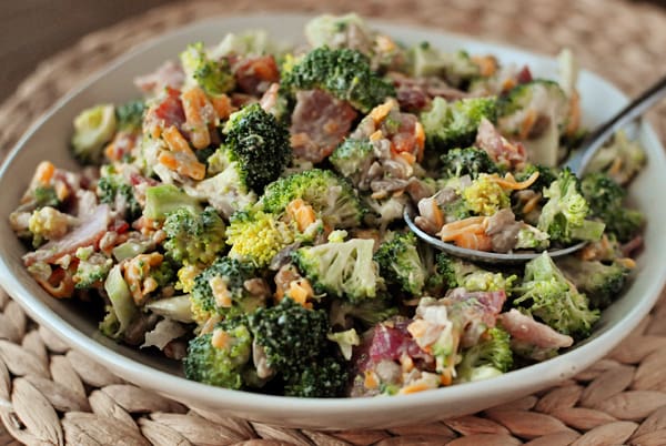 Full bowl of homemade broccoli salad with a spoonful of it on top ready to eat.