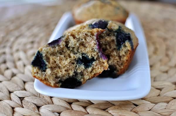 A blueberry muffin split in half on a white platter.