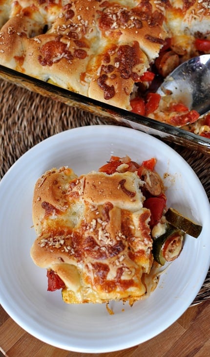 Top view of a pan of breadstick pizza casserole and a big helping of it on a white plate.