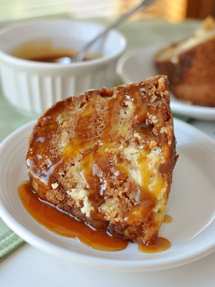 A piece of caramel drizzled apple bundt cake on a white plate.