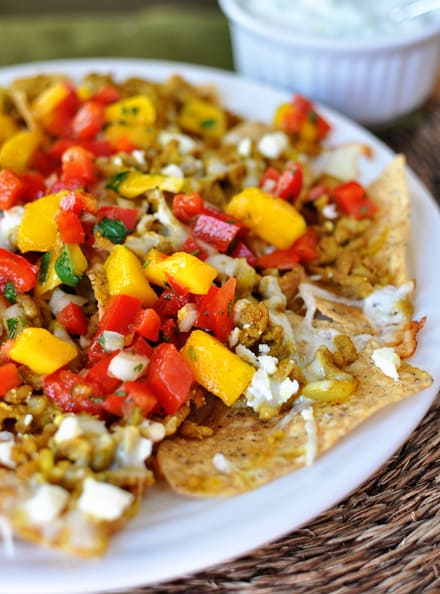 White plate full of mango and tomato-topped nachos.