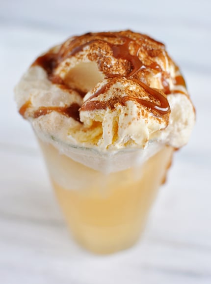 Clear glass with a caramel drizzled apple cider ice cream float.