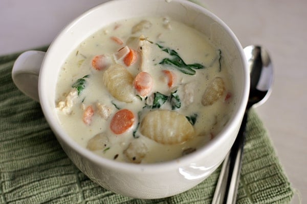 Top view of a white mug with chicken and vegetable gnocchi soup.