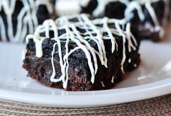 Oreo truffle brownie with white chocolate drizzle on white plate.