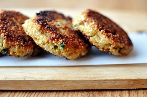 Golden brown cooked quinoa patties lined up on a piece of parchment paper.