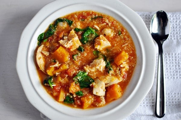 Top view of a white bowl with chicken, butternut squash, quinoa, and spinach stew.