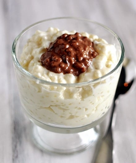 a small glass goblet with cheesecake rice pudding and a dollop of chocolate rice pudding in the middle