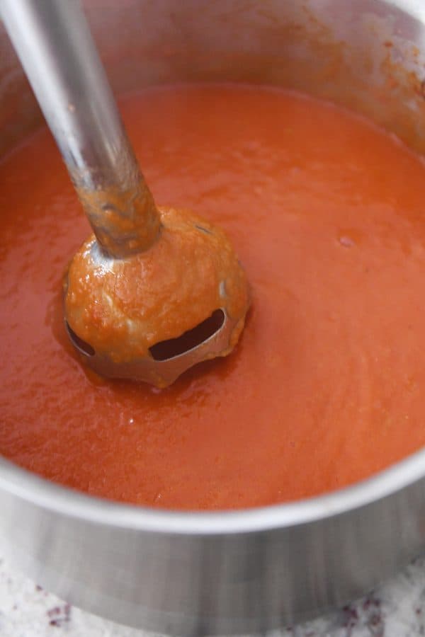 Blending classic tomato soup in pot with immersion blender.