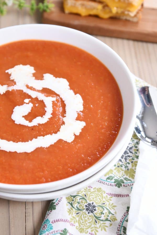 the best classic tomato soup in white bowl with swirl of heavy cream