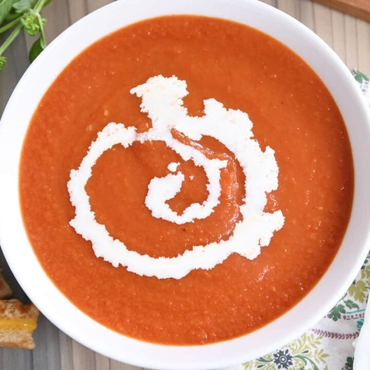 the best classic tomato soup in white bowl with swirl of heavy cream