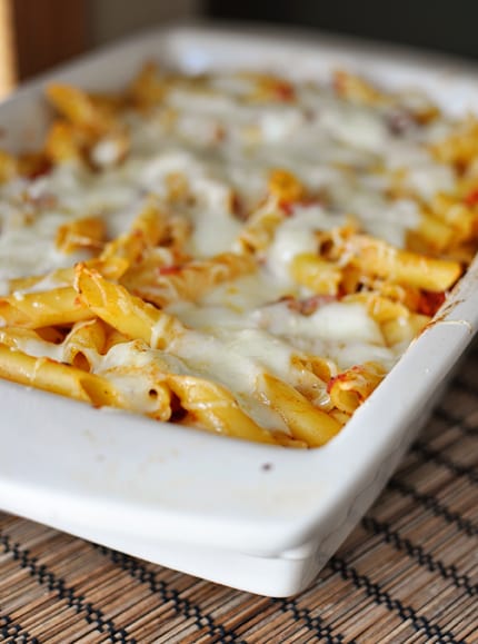 White casserole dish full of baked cheesy pasta.