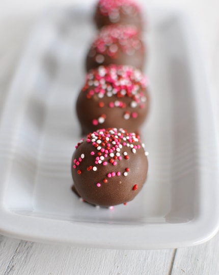 Sprinkle and chocolate dipped brownie truffles in a white rectangular dish.