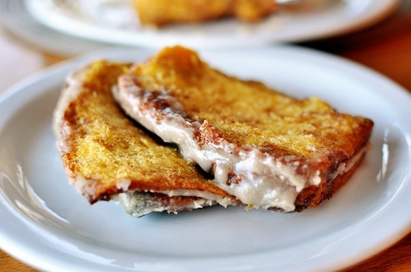 Two pieces of glazed pumpkin pull-apart bread on a white plate.