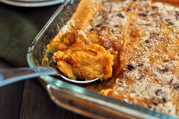 A clear casserole dish with cooked, streusel-topped sweet potato casserole.