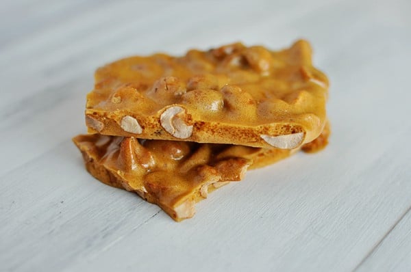 Two pieces of peanut brittle on top of each other on a light countertop.