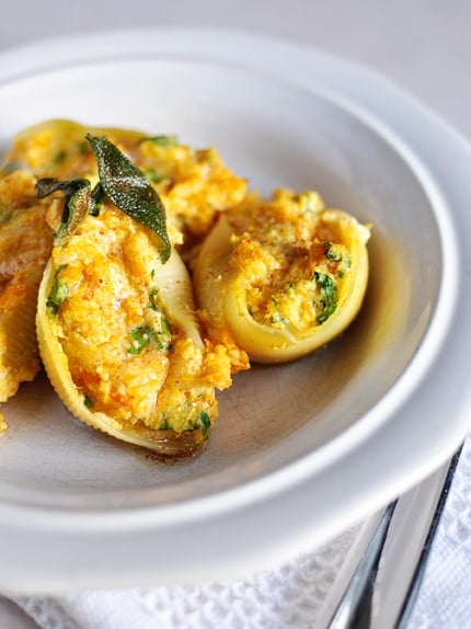 A white plate with stuffed butternut squash and sage pasta shells.