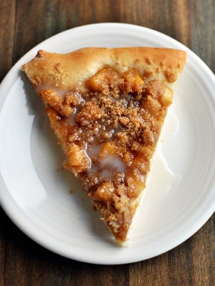 Top view of a slice of apple cinnamon dessert pizza on a white plate.