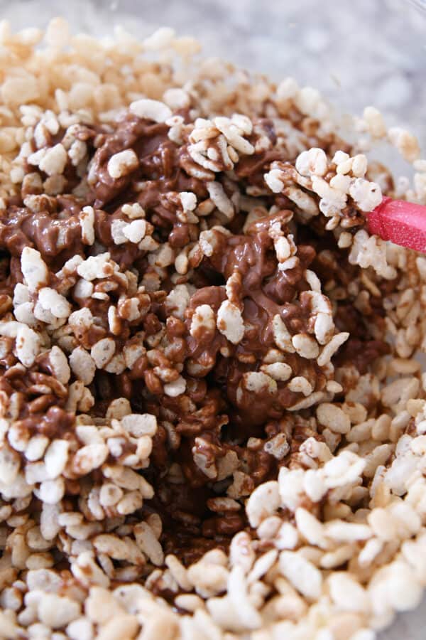 Stirring rice krispies into peanut butter chocolate mixture.