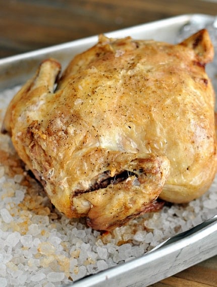 A whole roasted chicken on a bed of rock salt.