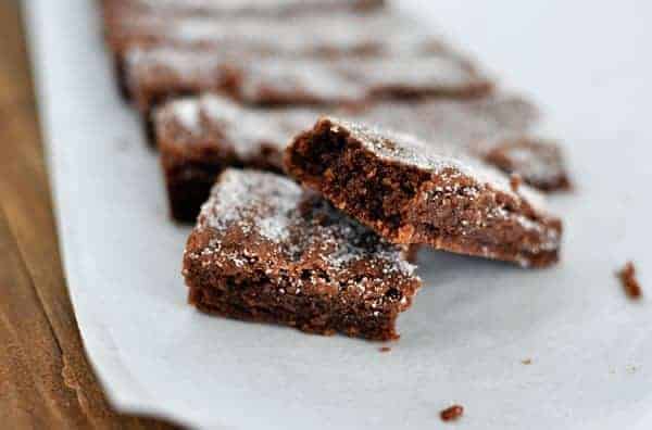 Powdered sugar dusted chocolate shortbread fingers on a piece of parchment.