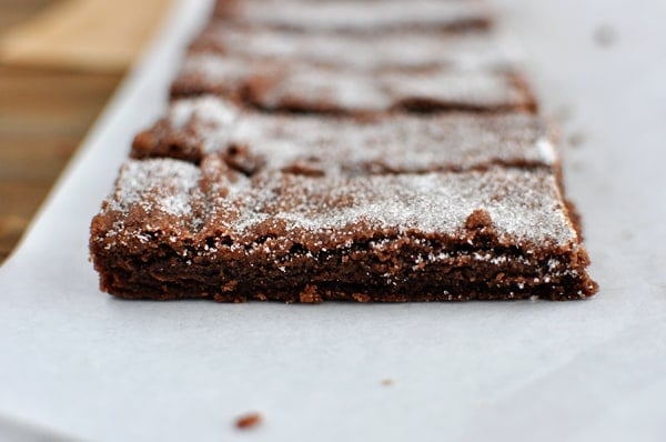 Side view of chocolate shortbread fingers dusted with powdered sugar.