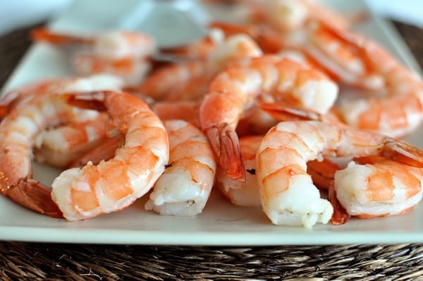 A white platter of cooked shrimp.