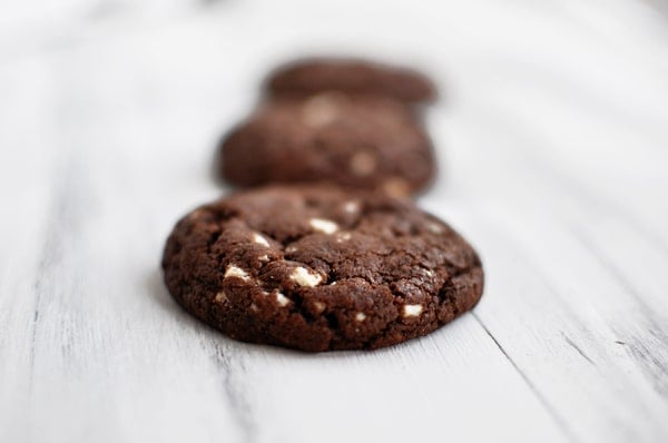 Chocolate cookies with white chocolate chunks lined up in a row.