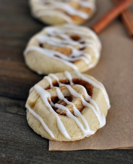 Top view of three cinnamon roll sugar cookies drizzled with white icing.