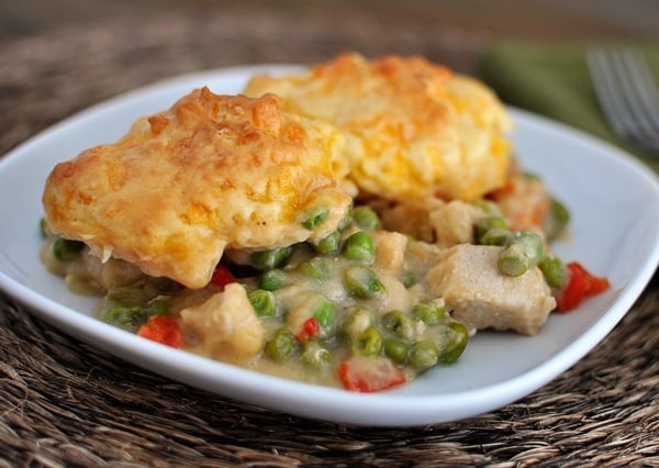 A white plate with a chicken and vegetable filling topped with a cheddar biscuit topping.