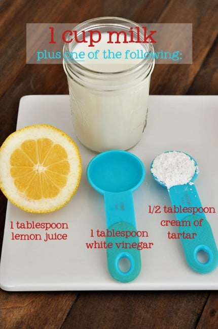 a white cutting board with a lemon, blue measuring spoons, and a mason jar of milk