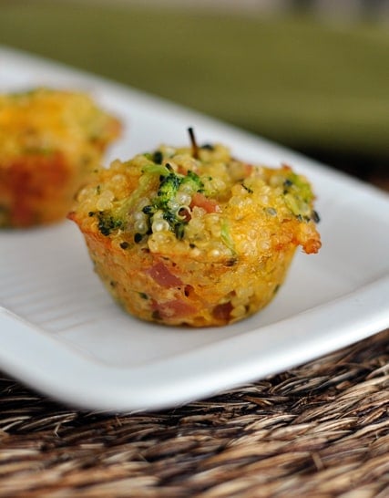 A cooked cheese, ham, and broccoli quinoa bite on a white rectangular platter.