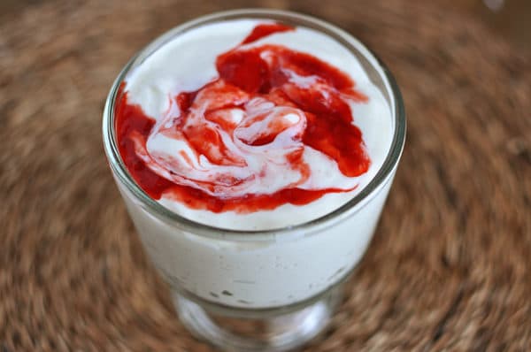 Top view of a glass goblet of homemade yogurt with a raspberry swirl inside.
